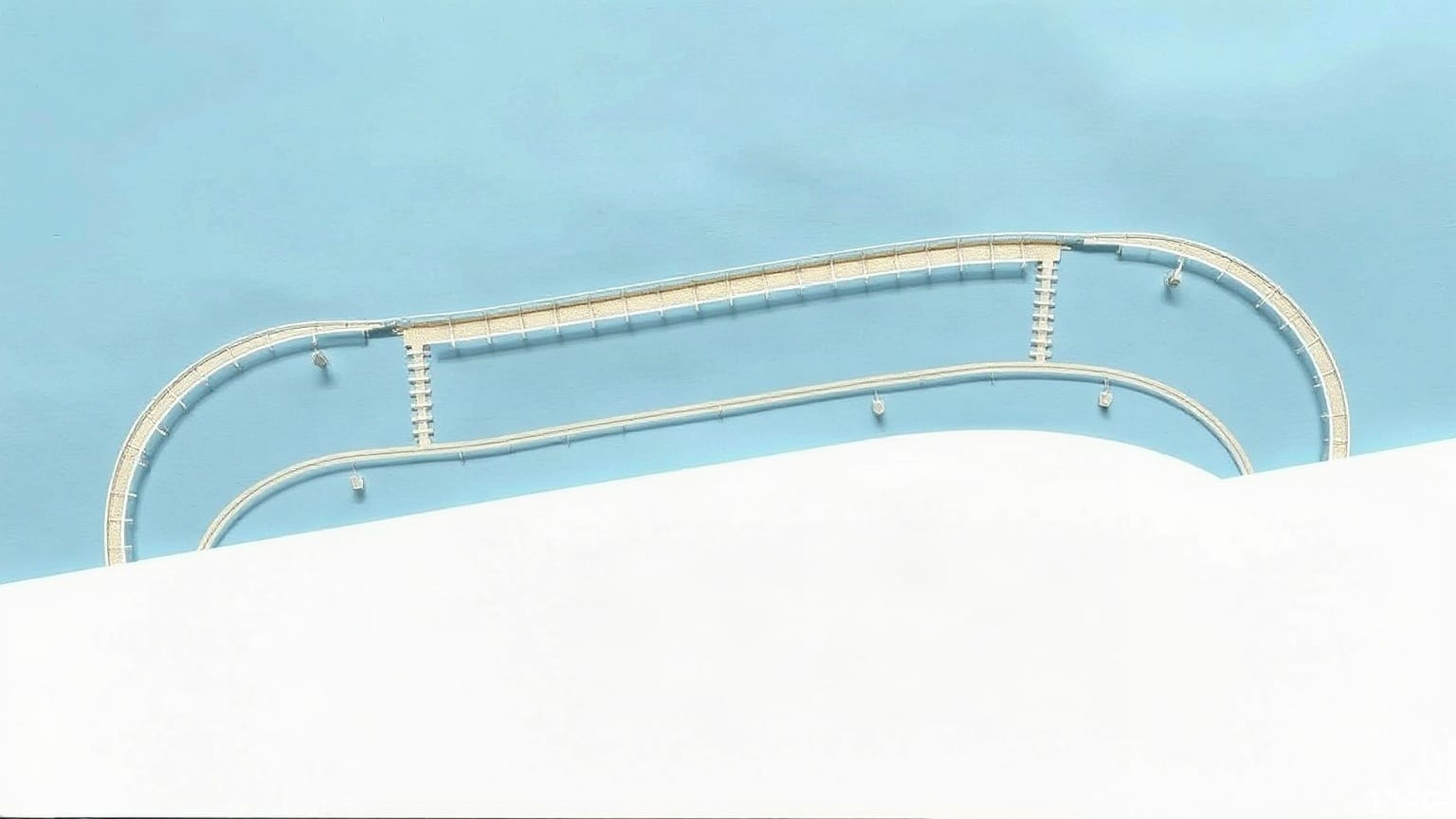 A pale oval racetrack with white rails set on a broad white band against a clear blue ground